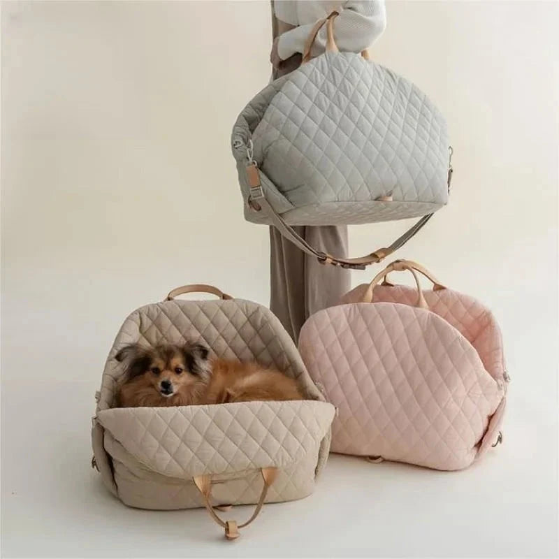 Quilted pet carrier in beige with a dog inside, surrounded by other quilted pet carriers in gray and pink on a light background.