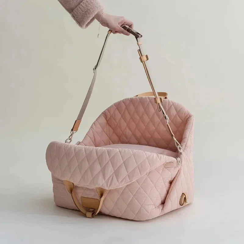 Pink quilted baby carrier with brown straps on a light background
