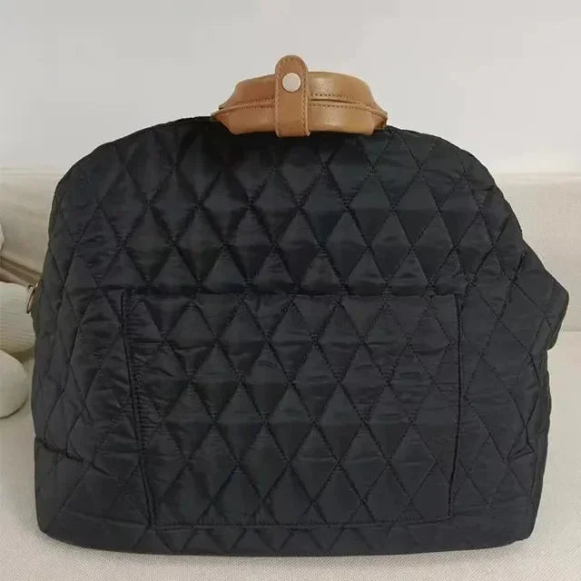 Black quilted backpack with a brown handle on a light background