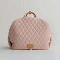 Quilted pink bag with wooden handle on a light gray background