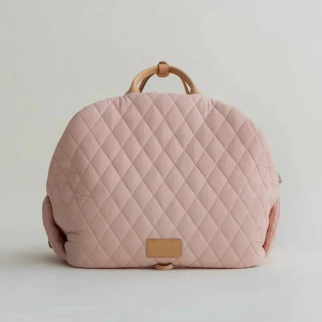 Quilted pink bag with wooden handle on a light gray background